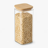 Square glass storage jar with bamboo lid filled with oats
