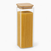 Tall square glass jar with bamboo lid filled with spaghetti