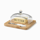 Square bamboo board with knife slot, white-handled butter knife and glass dome over a butter block
