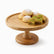 Round bamboo cake stand on a pedestal with ma'amoul cookies and pistachio baklava