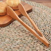 Bamboo kitchen tongs on a woven placemat with bread