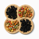Bamboo snack serving tray with 4 round compartments holding raisins and coated peanuts