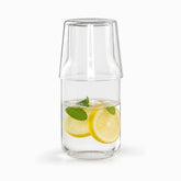 Glass bedside carafe with upside-down cup on top, filled with lemon and mint water