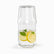 Glass bedside carafe with upside-down cup on top, filled with lemon and mint water