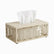 Rectangular beige metal tissue box cover with leaf cut-out pattern and tissue pulled through the top