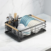 Black dish rack with plates, bowls and utensils on a marble kitchen counter