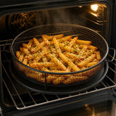 Black mesh air fryer basket and tray filled with crispy fries inside an open oven