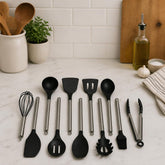 11 black silicone cooking utensils with steel handles laid out on a white marble kitchen counter