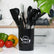 Black silicone cooking utensils standing in their black holder on a kitchen counter next to tomatoes and peppers