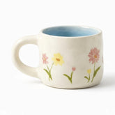 Cream ceramic mug with blue inside and hand-painted pink and yellow flowers