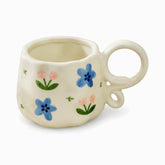 Cream ceramic mug with painted blue flowers, pink tulips and a looped ring handle