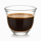Single clear glass Arabic coffee cup filled with dark Lebanese coffee and a foam layer on top