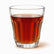 Single clear flared paneled tea glass filled with hot red tea, long panels visible through the tea