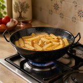 Homemade French fries frying in oil in a black speckled enamel pan on a gas stove
