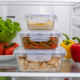 Glass containers with hummus, green bean stew and rice with chicken stacked on a fridge shelf