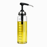 Clear glass pump dispenser filled with yellow oil, with black press pump, steel spout and measurement marks up to 450ml