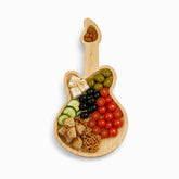 Guitar-shaped bamboo serving board with cheese, olives, tomatoes, cucumber, bread and walnuts, almonds in the pick-shaped well