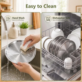 Hand scrubbing a stainless steel plate with a sponge under running water next to stainless steel plates loaded in a dishwasher rack
