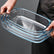 Hands holding 3 nested rectangular glass baking dishes by their textured handles