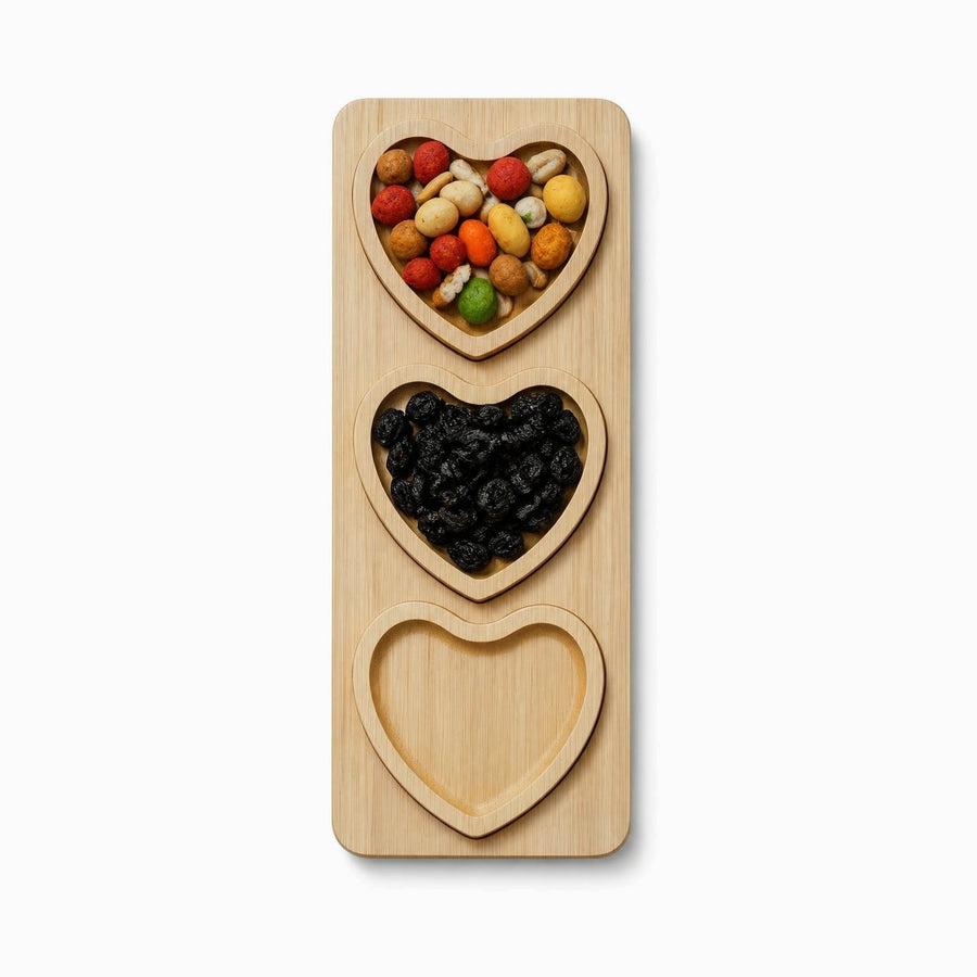Rectangular bamboo board with 3 removable heart-shaped plates holding coated peanuts and raisins, one plate empty