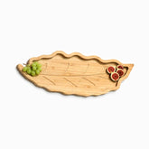 Leaf-shaped bamboo serving tray with carved veins, green grapes and fresh fig halves