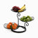 Black 3-tier metal fruit stand with leaf-shaped wire baskets holding grapes, bananas, green apples and oranges