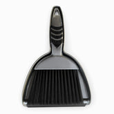 Silver mini dustpan with nested hand brush, black rubber grip pads and black bristles, top view