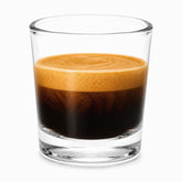 Single mini clear glass cup filled with an espresso shot and thick golden crema on top