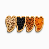 Bamboo serving tray with 4 heart-shaped compartments holding pistachios, raisins, almonds and dried apricots