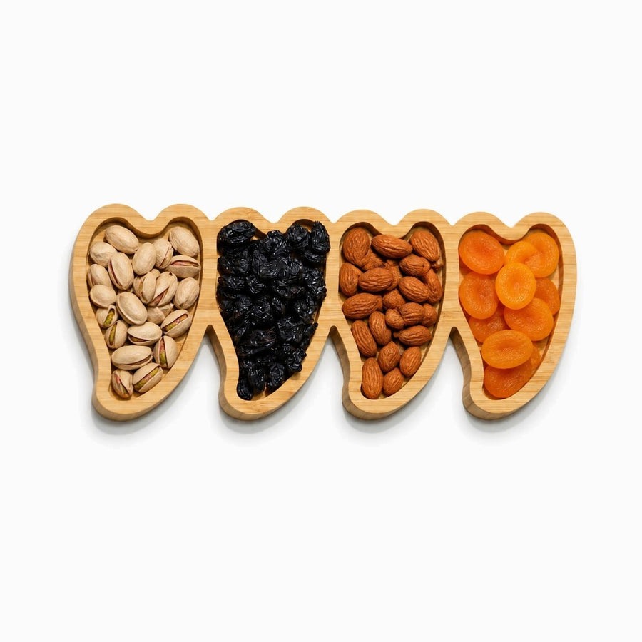 Bamboo serving tray with 4 heart-shaped compartments holding pistachios, raisins, almonds and dried apricots