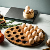 Oval wooden egg tray half filled with eggs on a marble counter with rosemary