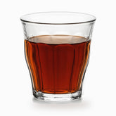 Single clear paneled tea glass filled with hot red tea, panels visible through the tea
