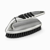Silver plastic scrub brush with black rubber grip pads, arched handle and black bristles