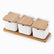 3 white porcelain canisters with bamboo flip lids and spoons on a long bamboo tray