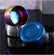 Rainbow and blue round ashtrays tipped on their sides beside silver ones on a dark reflective surface, showing the inside and the base