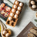 Rectangular wooden egg tray with eggs next to muffins, bread and a bamboo steamer