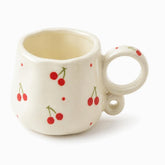 Cream ceramic mug with painted red cherries, tiny red dots and a looped ring handle