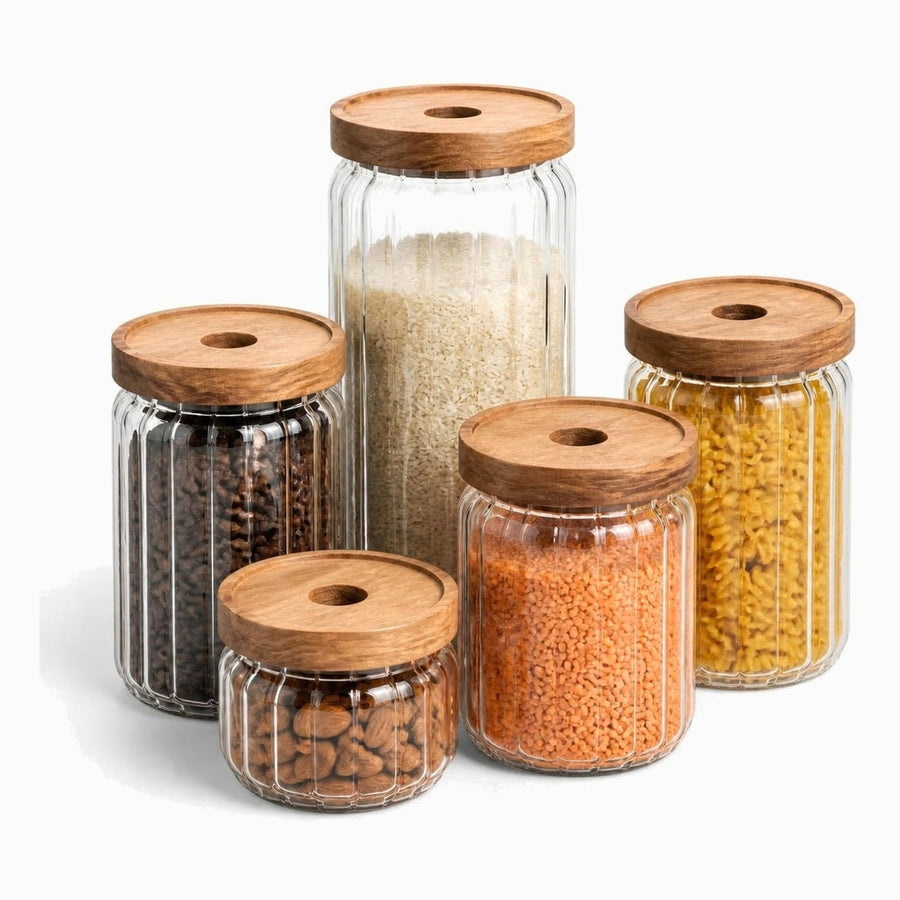 5 ribbed glass jars with burnt wood lids filled with rice, coffee beans, almonds, lentils and pasta