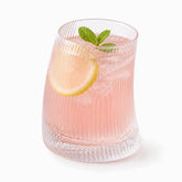 Short curved ribbed glass with pink rose-water lemonade, lemon slice and mint