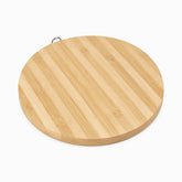Round bamboo cutting board with metal hanging ring, angled view
