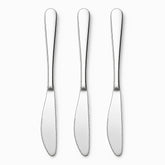 Three mirror-polished stainless steel table knives with serrated edges lined up in a row