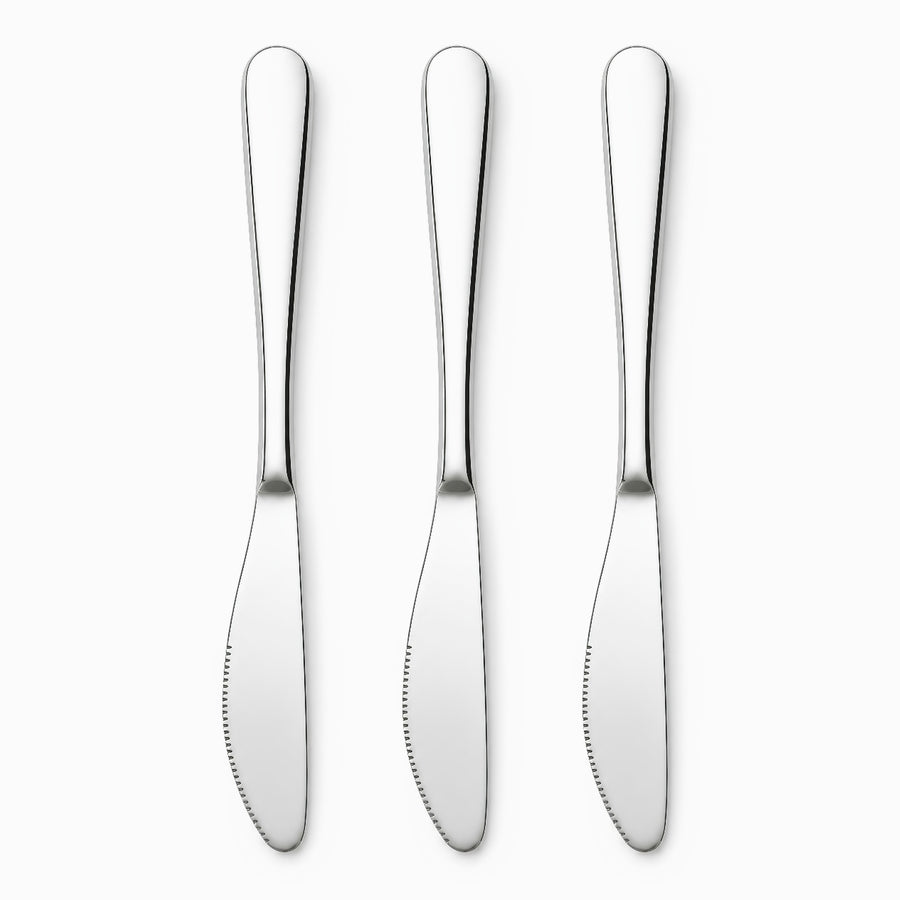 Three mirror-polished stainless steel table knives with serrated edges lined up in a row
