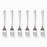 Six stainless steel dessert forks with engraved wave handles lined up in a row