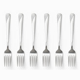Six stainless steel dinner forks with engraved wave handles lined up in a row