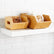 Small and large bamboo bins with side handles on a white shelf, one holding walnuts in a clear container and the other holding bagged cashews