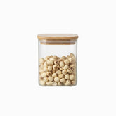 Small square glass storage jar with bamboo lid filled with lotus seeds