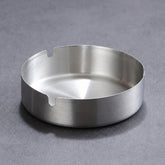 Brushed stainless steel ashtray on a dark grey surface