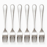 Six mirror-polished stainless steel dinner forks with 4 tines lined up in a row