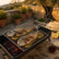 Grill basket with two whole sea bream and lemon slices over a charcoal mangal, with pita and tahini