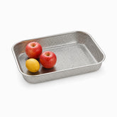 Perforated stainless steel drainer tray with 2 red apples and a lemon, half left empty